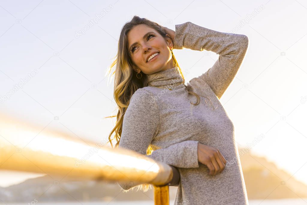 sunset portrait of beautiful young woman at sea shore