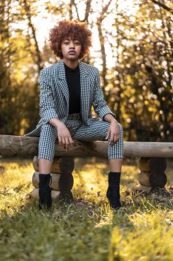 Parkta bankta oturan şık, genç ve çekici Afrikalı Amerikalı kadın.