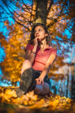 Sonbahar parkında genç güzel bir kadının günbatımı portresi.