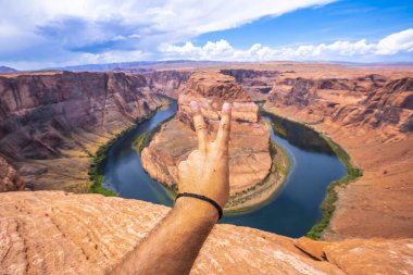 Arizona 'daki Grand Canyon Ulusal Parkı' nda Horseshoe Bend 'e karşı şeytan boynuzu hareketi yapan adam.