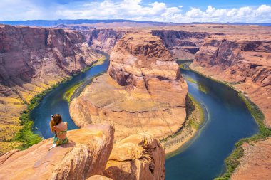 Kayaya oturmuş, Arizona 'daki Grand Canyon Ulusal Parkı' nda Horseshoe Bend 'e bakan bir kadın.