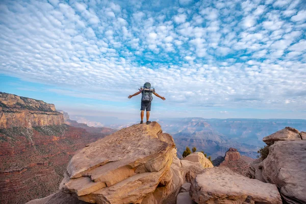 man standing on top of rock looking at Grand Canyon National Park, Arizona, USA