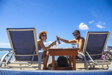 Biralı mutlu çift kumsalda şezlongda oturuyor kumsaldaki şezlonglarda 