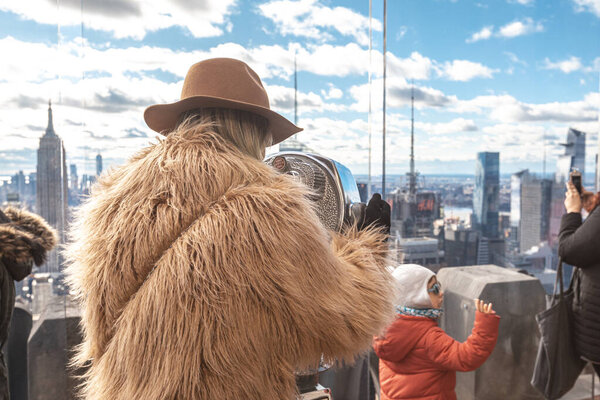 New York, United States - January 5, 2020: woman enjoying amazing view of New York City through touristic telescope