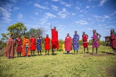 Masai Mara, Kenya - August 2018: A group of Masais explaining the Masai tradiones to a group of tourists and one of them jumping