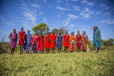 Masai Mara, Kenya - August 2018: Local and Caucasian tourists with young Masais
