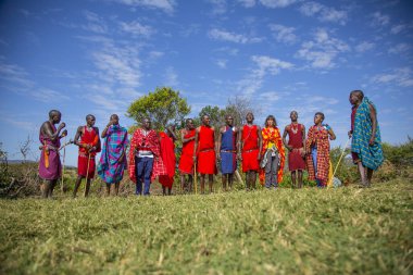 Masai Mara, Kenya - August 2018: Local and Caucasian tourists with young Masais