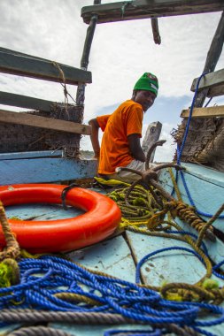 Wasini, Kenya - August 2018: African man in t-shirt on the front of the traditional Wasini boat looking at the sea