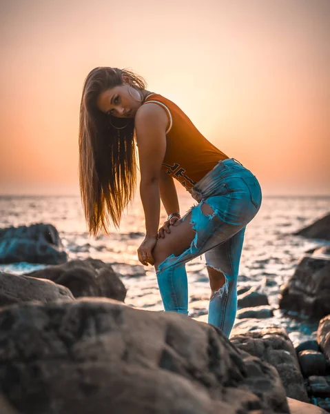 portrait of beautiful young woman at sea shore on sunset