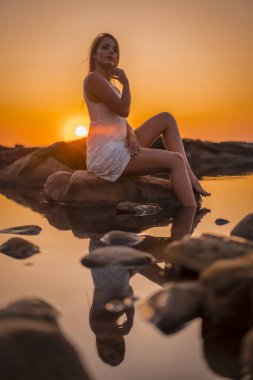 sunset portrait of beautiful young woman at sea shore clipart