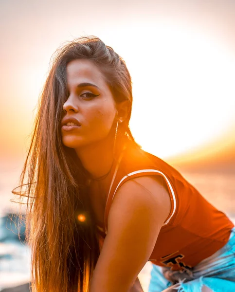 portrait of beautiful young woman at sea shore on sunset