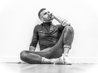 Yerde oturan çekici genç adamın portresi.