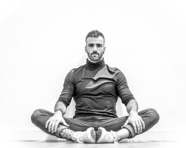 Yerde oturmuş meditasyon yapan çekici genç bir adamın portresi.