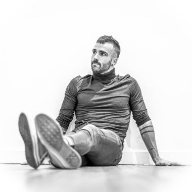 Yerde oturan çekici genç adamın portresi.