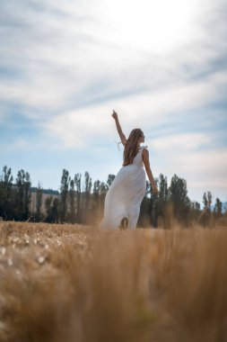 Kırsal kesimde beyaz elbise giyen güzel bir genç kadının portresi.