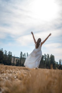 Kırsal kesimde beyaz elbise giyen güzel bir genç kadının portresi.