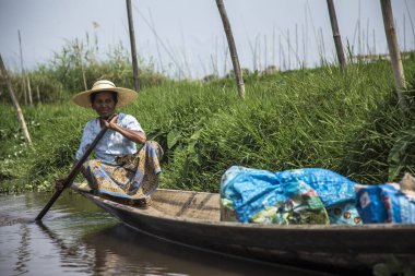 Inle Lake, Myanmar - Spring, 2018: a woman with the crop covered for her home in a boat
