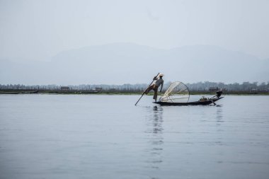 Inle Lake, Myanmar - Spring, 2018: local fisherman moving with his feet on the boat