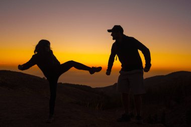 Gün batımında mutlu bir çiftin siluetleri.