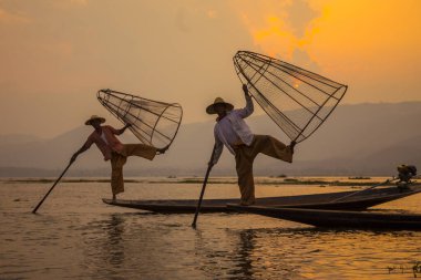 Inle Lake, Myanmar - Spring, 2018: two traditional fishermen of Lake Inle Lake lifting the net and holding it with the feet
