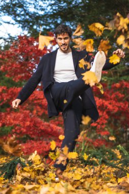 Güz parkında poz veren takım elbiseli yakışıklı genç adam.
