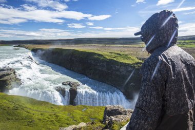 İzlanda 'daki Gullfoss şelalesine bakan genç bir turist.