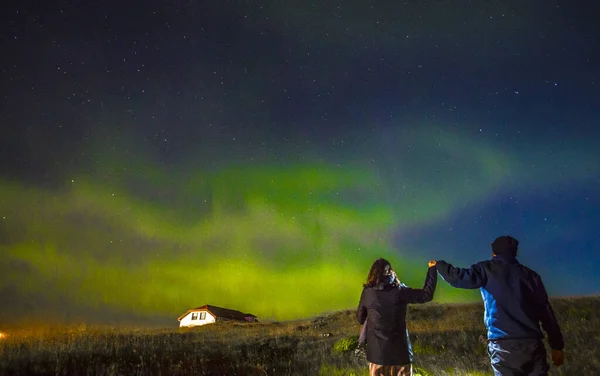 couple looking at Reykjanesskaginn landscape with Aurora Borealis, Iceland
