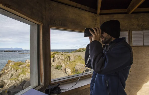 A young man looking at seals with spyglasses on the Skagaheioi peninsula in Iceland