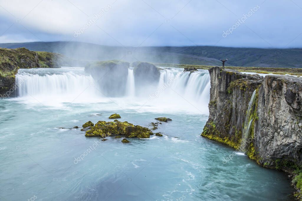 Godafoss waterfall, a young woman enjoying the waterfall. Iceland