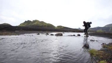 Landmannalaugar yolunda soğuk nehri geçen genç bir kadın. İzlanda