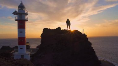 Punta de Teno, Tenerife fenerinde gün batımında genç bir adam