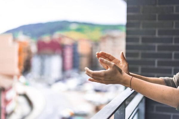 Hands of a young woman applauding and in the background the city to the toilets every day at 8 in the afternoon. Pandemic coronavirus