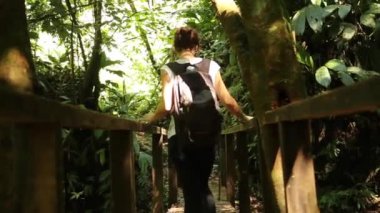 Yojoa Gölü üzerindeki Cerro Azul Meambar Ulusal Parkı (Panacam) ahşap köprüsünde yürüyen genç bir kadın. Honduras