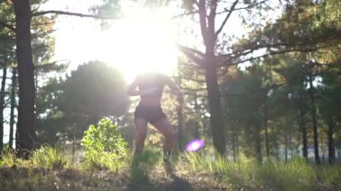 Zumaia, Gipuzkoa / İspanya; Eylül 2019: Çömelme ve zıplama egzersizi, ormanda spor yapan genç bir kadın