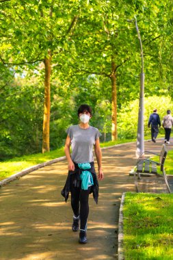 Coronavirus salgını, parkta sosyal mesafeye saygısı olan genç bir kadının portresi.