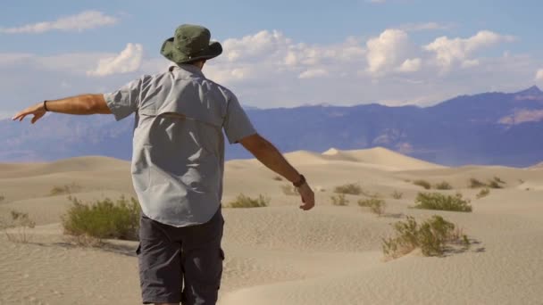 一个穿着灰色衬衫的年轻人正在加利福尼亚州死亡谷的沙漠里享受着 — 图库视频影像
