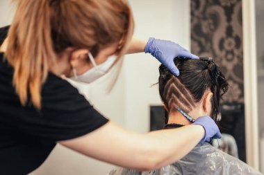 Maske traşlı kuaför ve müşteriye üçgen çizimler yapıyor. Covid-19 salgınında kuaförlerin güvenlik önlemleriyle yeniden açılıyor.