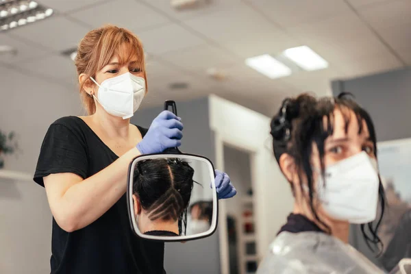 Hairdresser teaching in court in the mirror. Reopening with security measures of Hairdressers in the Covid-19 pandemic