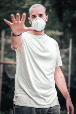 Maskeli genç bir adam, eli açık beyaz bir gömlek. Sağlık acil durumu, salgın Covid-19
