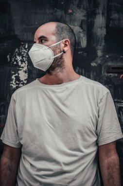 Beyaz gömlekli, maskeli, siyah metal kapılı genç bir adam. Sağlık acil durumu, salgın Covid-19