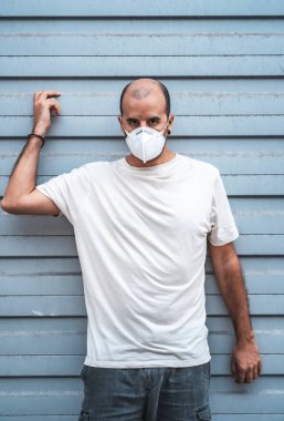 Maske fabrikasının dışında maskeli öfkeli bir genç adam. Sağlık acil durumu, salgın Covid-19