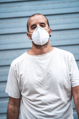 Maske fabrikasının dışında maskeli genç bir adam. Sağlık acil durumu, salgın Covid-19