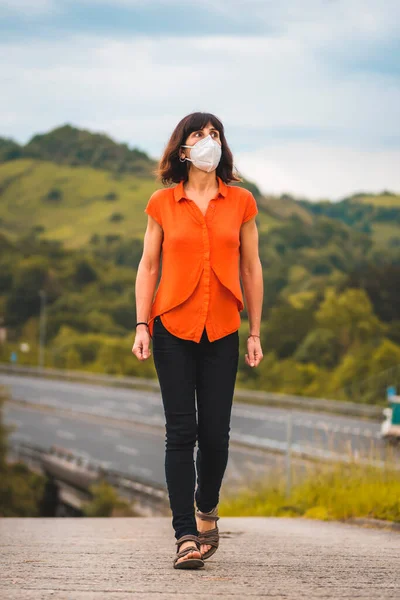 Egy Fiatal Kaukázusi Védő Maszkkal Narancssárga Inggel Háttérben Egy Autópályával — Stock Fotó