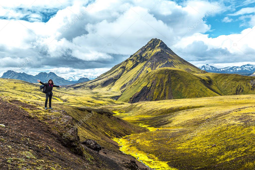 A young woman on a green mountain and a beautiful river of moss on the 54 km trek from Landmannalaugar, Iceland