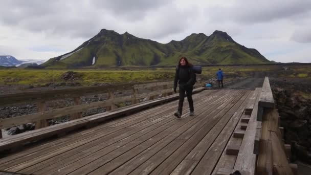 一名年轻女子 背着背包 在距离Landmannalaugar 54公里的长途跋涉中 穿过一座木桥 — 图库视频影像