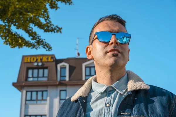 Lifestyle Nuori Valkoihoinen Mies Kädet Ristissä Takki Aurinkolasit Hotellin Taustalla — kuvapankkivalokuva
