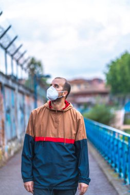 İlk yürüyüşlerinden birinde maske takmış genç beyaz bir adam güven eksikliği içinde yürüyor. Kontrolsüz Covid-19 salgınının ilk adımları