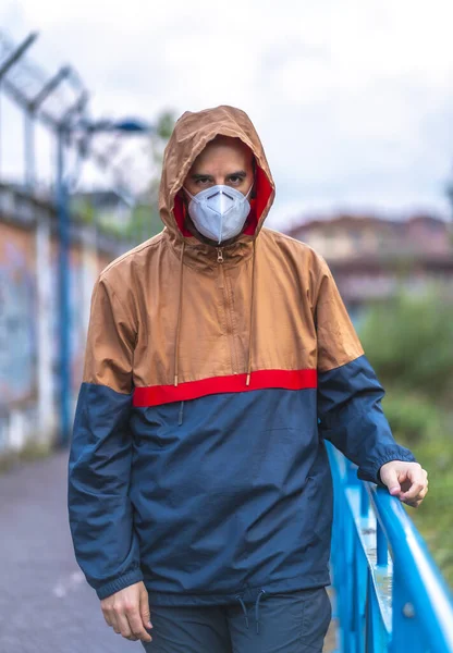 A young Caucasian man in mask walking through a park. First walks of the uncontrolled Covid-19 pandemic
