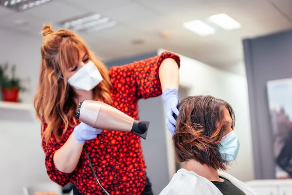 Szőke Fodrász Maszkkal Kesztyűvel Ügyfél Barna Haját Szárítja Hajszárítóval Újbóli — Stock Fotó