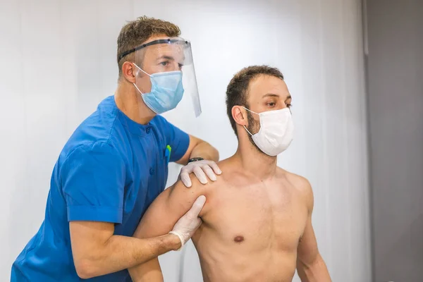 按摩师一种有屏风和面罩的理疗师 提供肩部按摩对Coronavirus大流行病Covid 19采取保护措施的理疗 治疗性脊椎按摩 — 图库照片